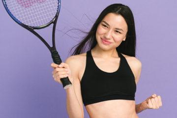 A young woman enthusiastically brandishing a Wilson tennis racket against a pastel purple background, demonstrating how fun the sport can be for a guide on how to get into playing tennis as a hobby